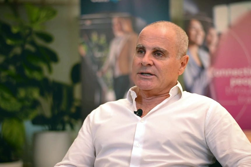 in a white business shirt with a microphone clipped to it.