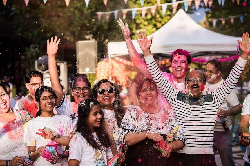 A crowd of people covered in bright colours enjoying themselves.