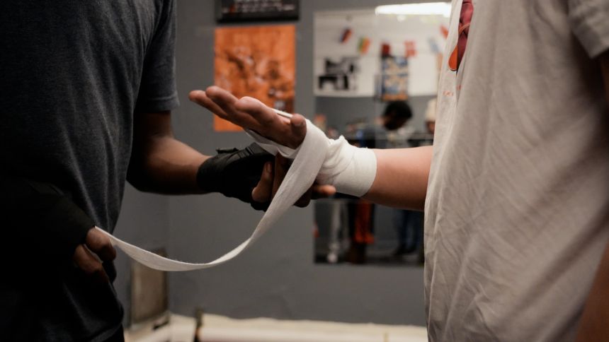 A student has his hands taped for boxing.