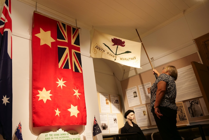 A woman displays an historical flag symbolising a march that took place in 1915.