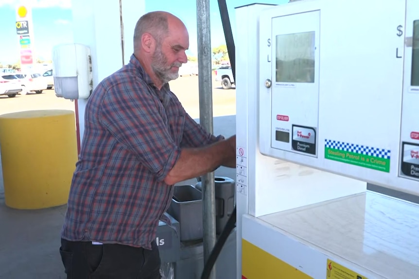 A man puts a nozzle back in the fuel pump