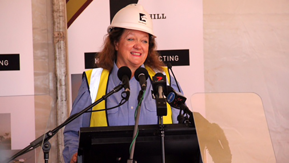 A woman in a hardhat speaks from a podium. 