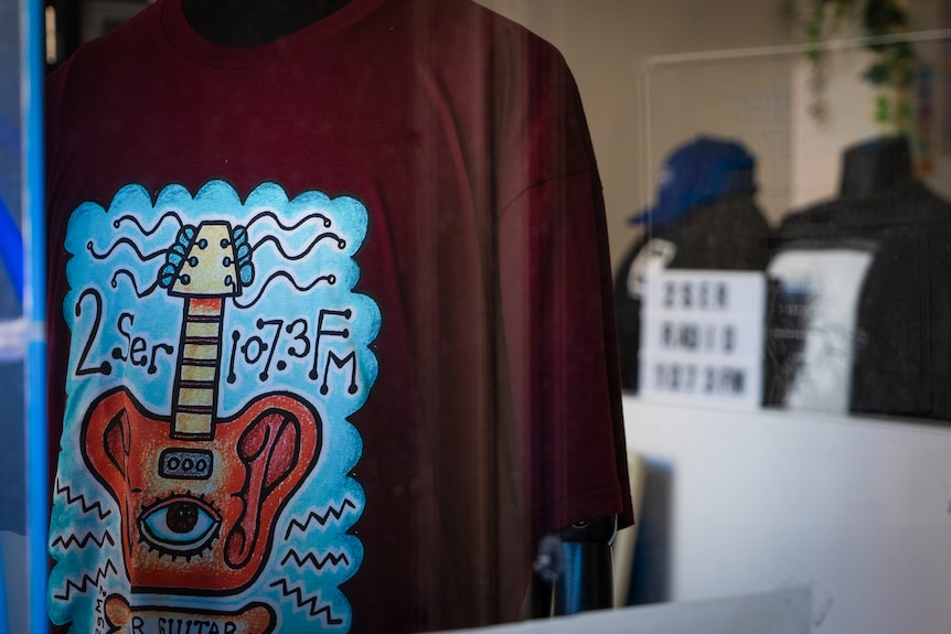 A maroon shirt with a cartoon guitar on the front, above reads 2ser 107.3 FM.