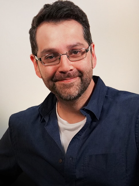 A man in glasses smiles at the camera