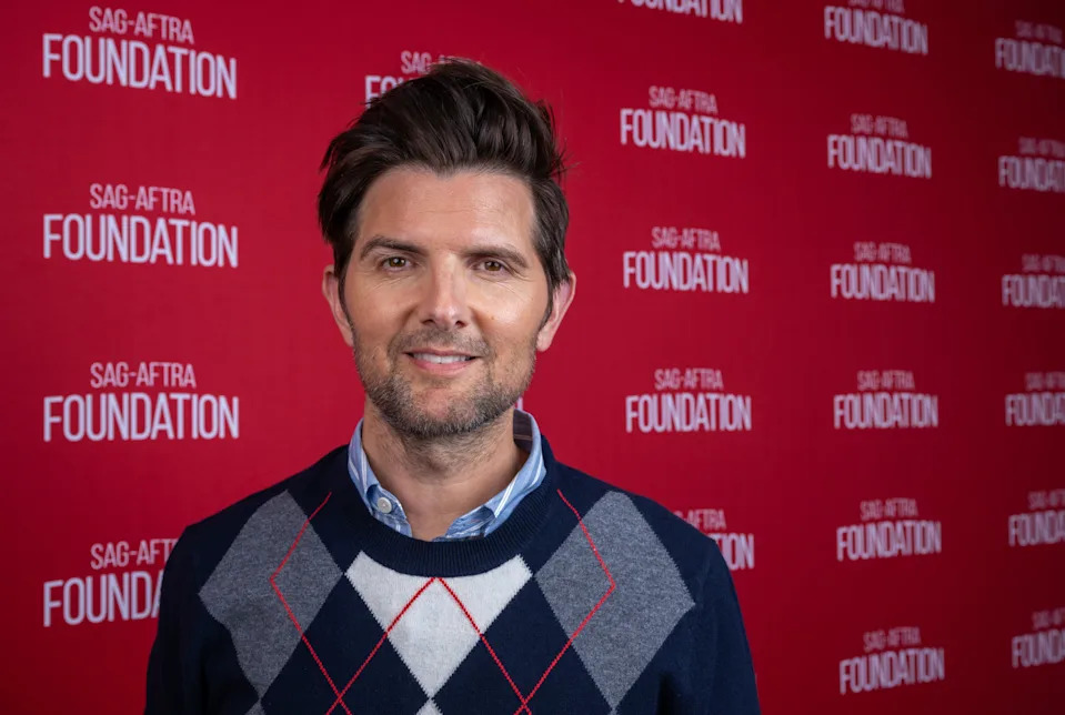 Adam Scott in argyle sweater at SAG-AFTRA Foundation event, standing in front of branded backdrop
