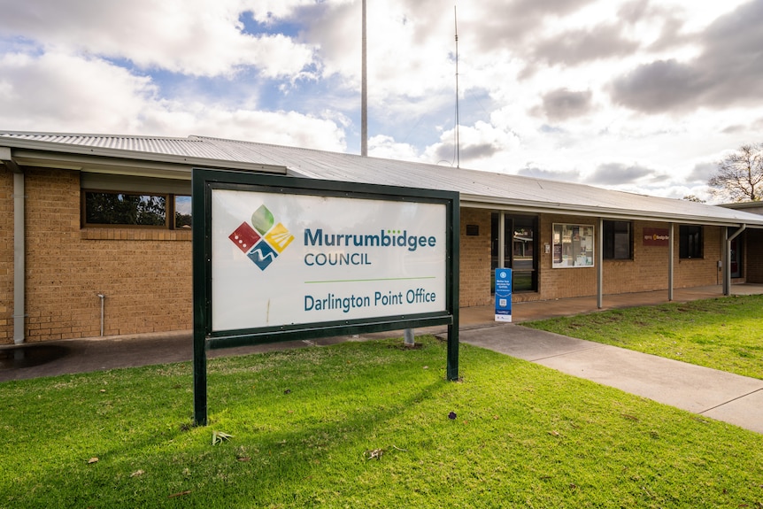 A sign reading 'Murrumbidgee Council, Darlington Point office', stands outside of a low-set brick building.