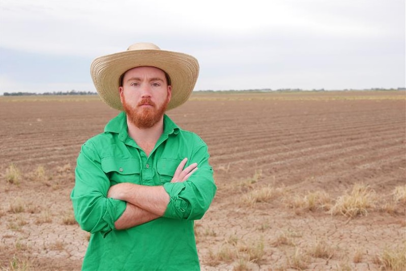 Cotton grower Sam Ryan stands in front of a ploughed paddock.