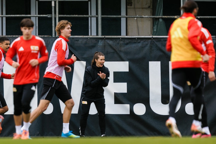 Marie Louise Eta claps as players train in front of her