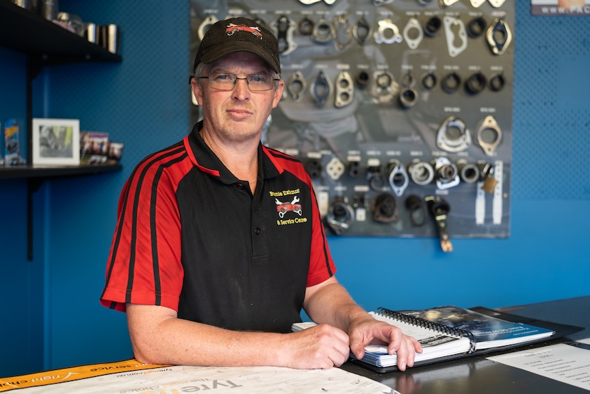 Man in polo and cap stands at table for portrait
