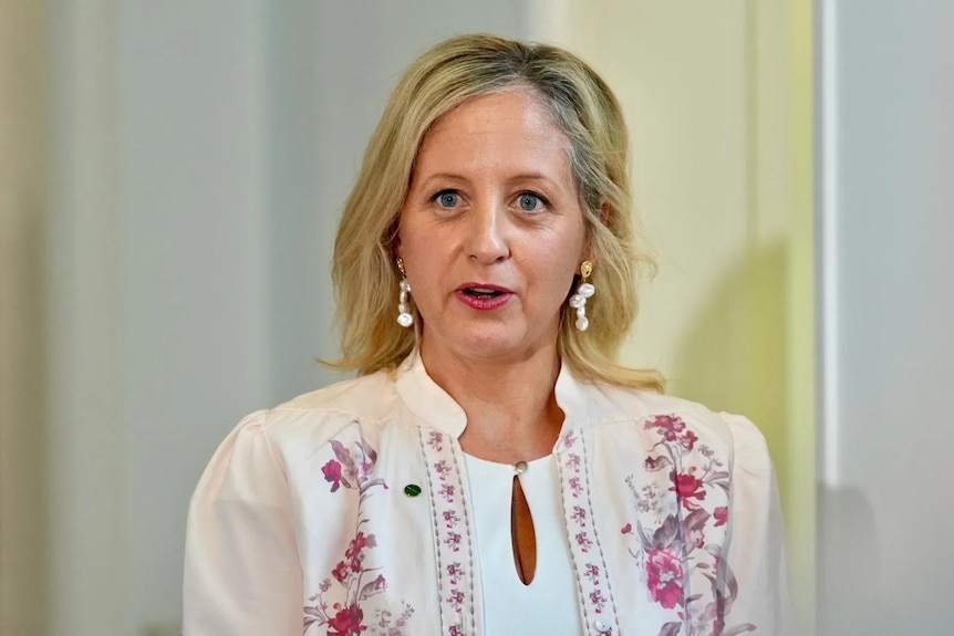 A middle-aged blonde woman in a floral blouse.