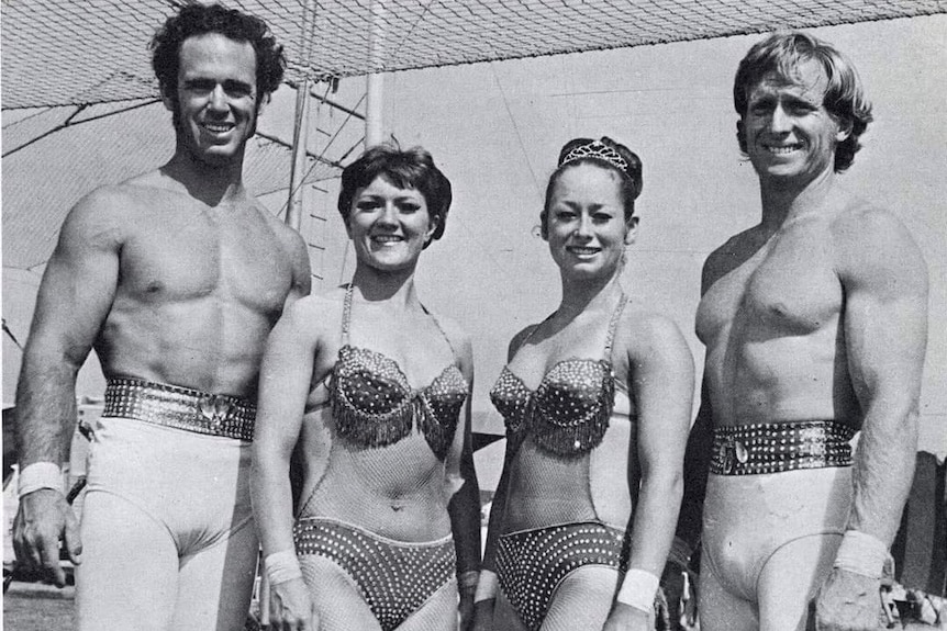 A black and white photo of two men and two women gymnasts in costume.