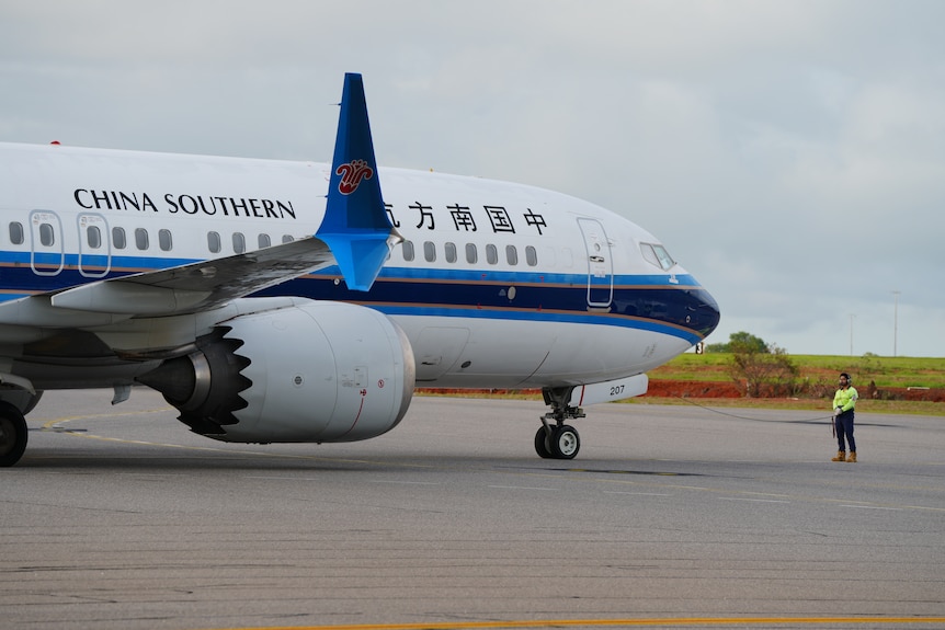 A blue and white plane taxiing towards an airport runway, on the side of the aircraft reads: China Southern Airlines