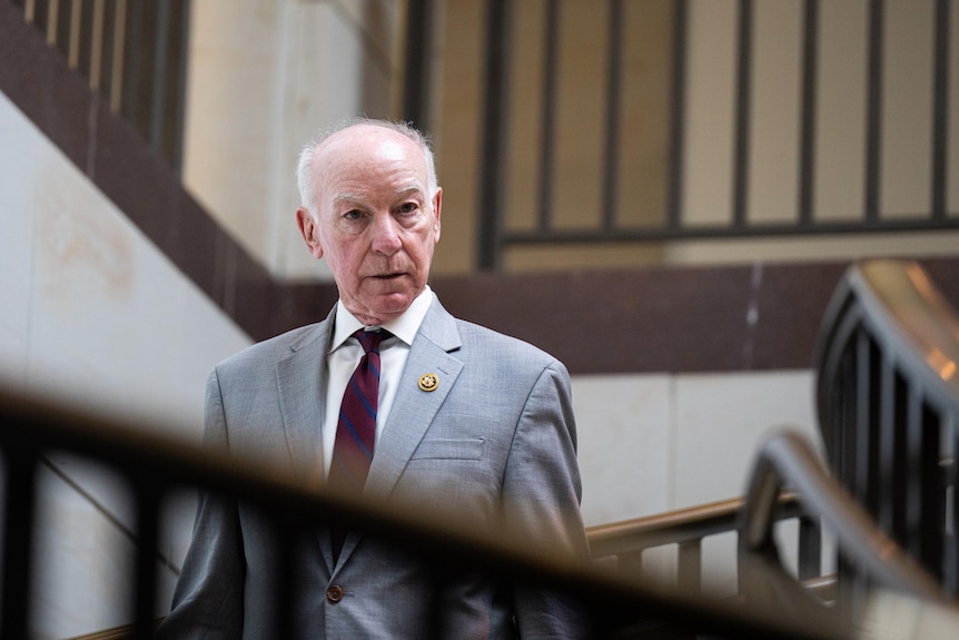 Man in a grey suit with a burgundy tie standing in the US Capitol.