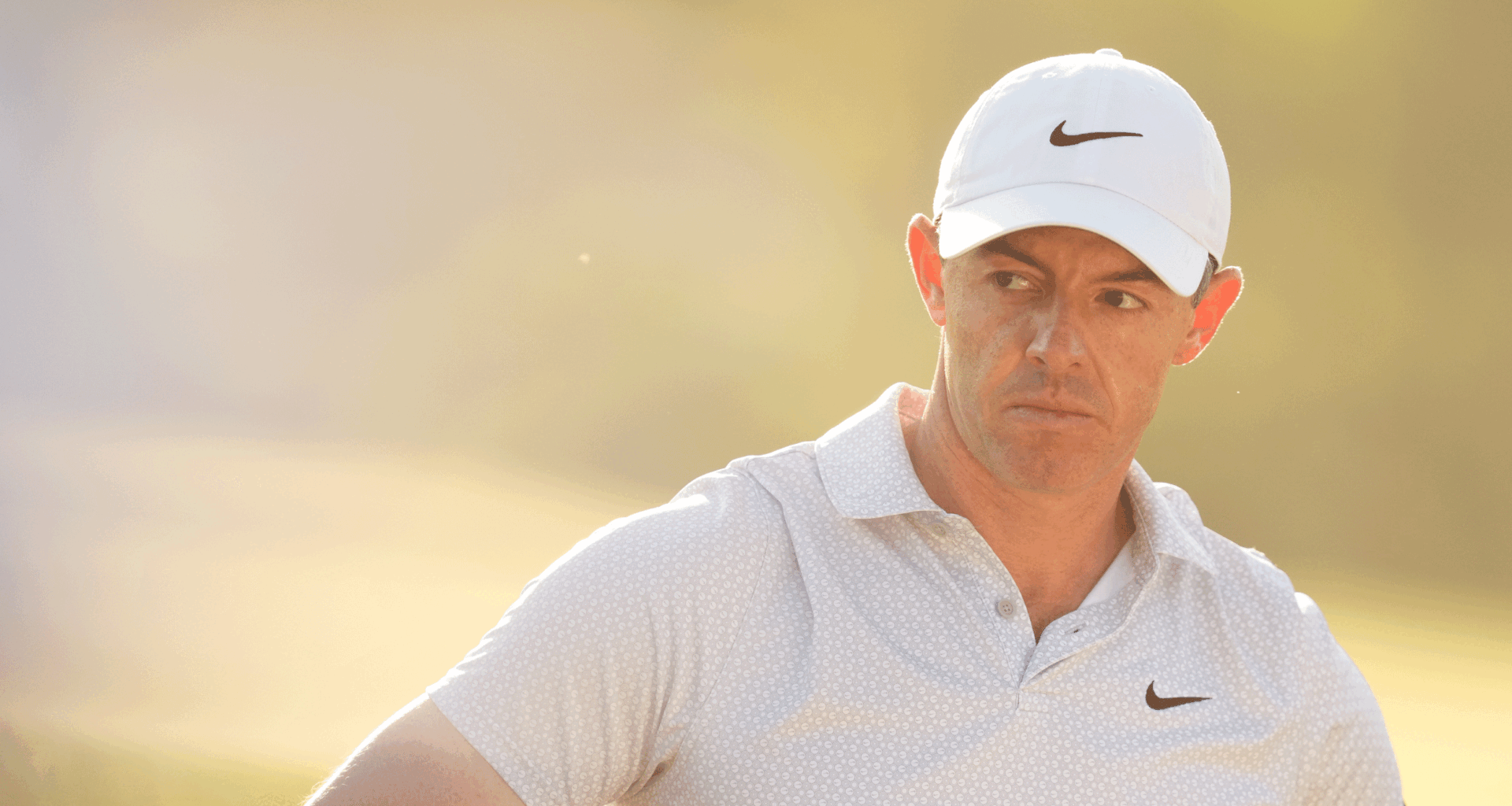 Rory McIlroy looks on during round two of The Masters in 2026 while wearing a white Nike cap and light polo shirt