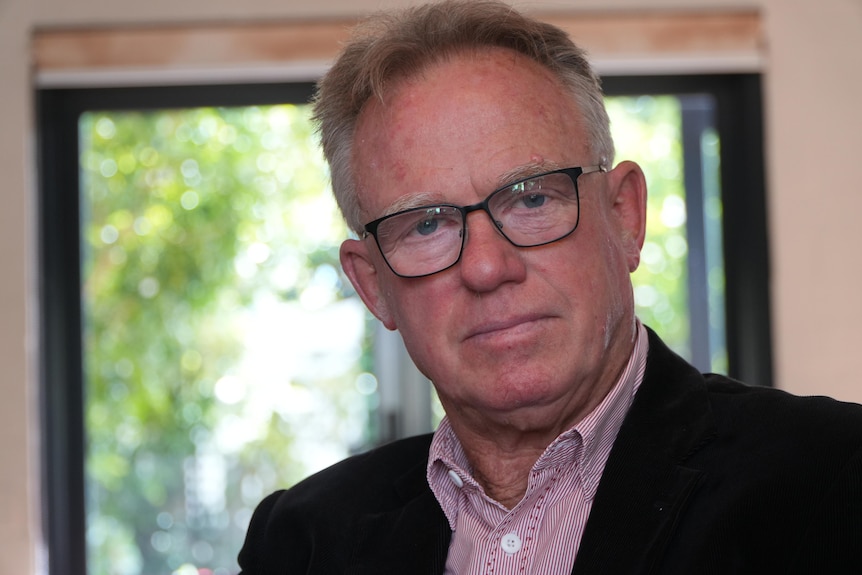 A tight head and shoulders shot of former state Labour MP Martin Whitely indoors, wearing a dark suit jacket and pink shirt.