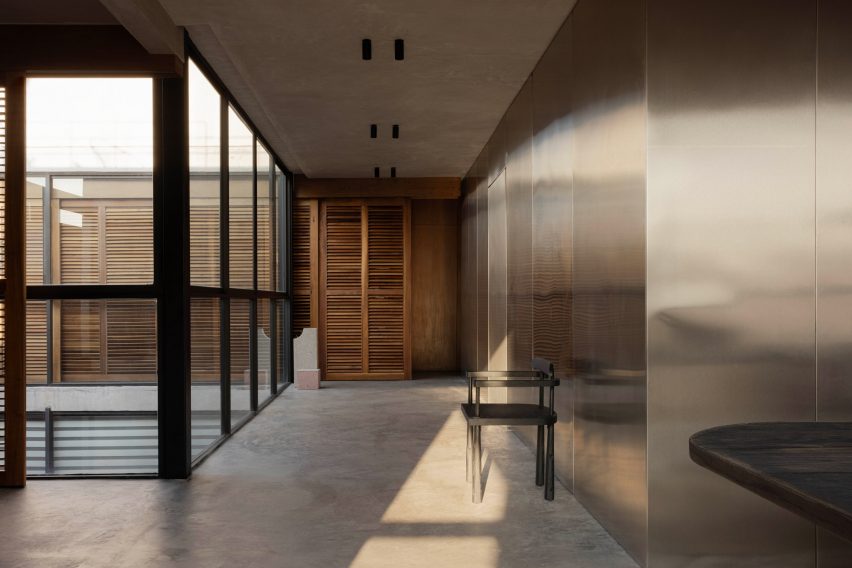 A lightwell wrapped in floor-to-ceiling glass opposite walls clad in stainless steel