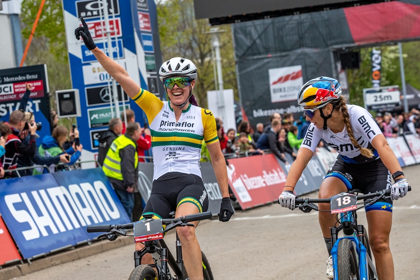 Bec Henderson celebrates with her hand in the air as Pauline Ferrand-Prévot looks over her shoulder