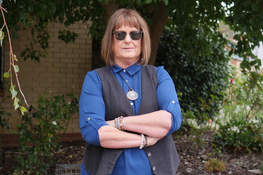 A woman stands with her arms crossed. 