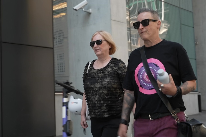 Two women, one with short hair,  walking outside court