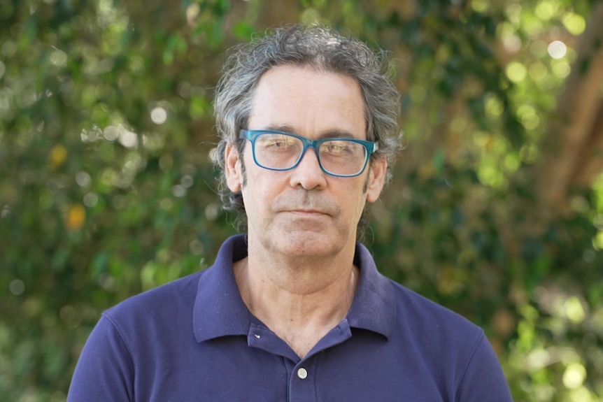 A man stands in front of trees