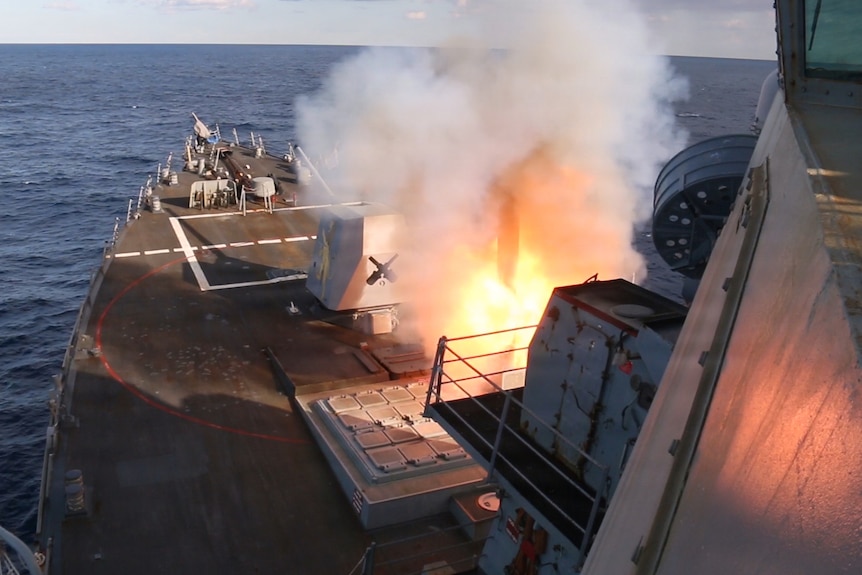 A missile launch from the front of a military vessel in the ocean.