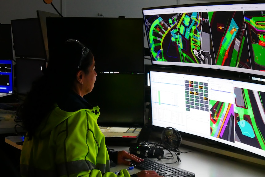 A worker sits behind several monitor screens in Boddington gold mine's control room.