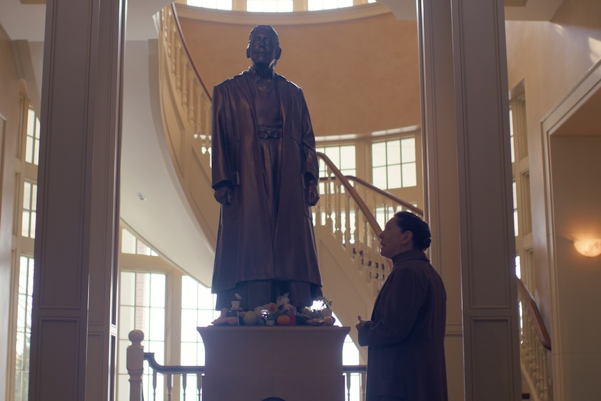 Ann Dowd as Aunt Lydia looking at a statue of herself