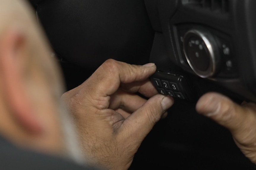 A man's hands installing a keypad on a car dash