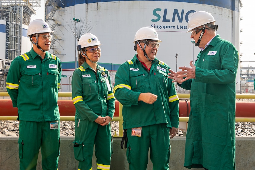 Anthoy Albanese wearing green workwear and a helmet speaks to three others wearing similar safety clothes.