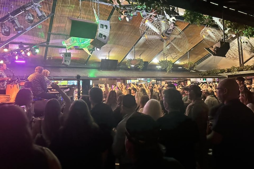 A band plays in a packed live music venue.