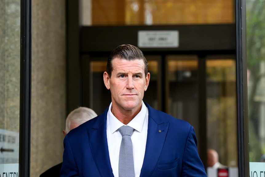 Ben Roberts Smith in a blue suit, white shirt, outside court on a sunny day.