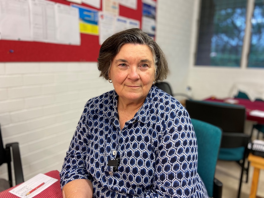 A woman with a short greying bob looks into the camera. 