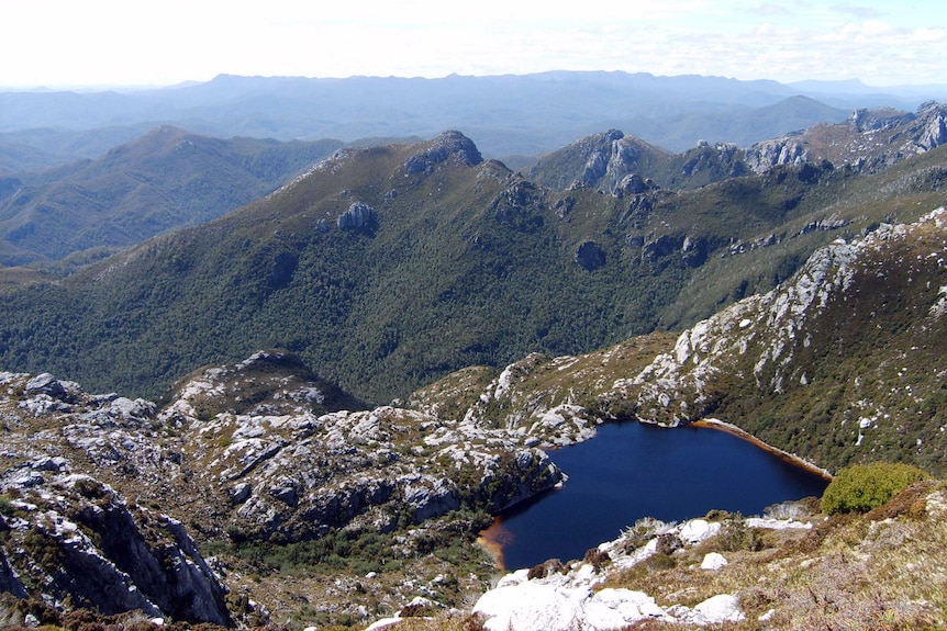 Mountain ranges in Tasmania's southwest with a small lake in the foreground.