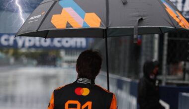 Oscar Piastri holds an umbrella as a superimposed lightning bolt hits his umbrella at the Miami GP