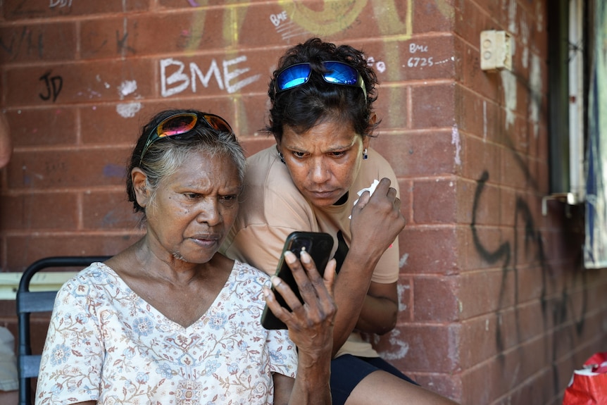 two women look at a phone