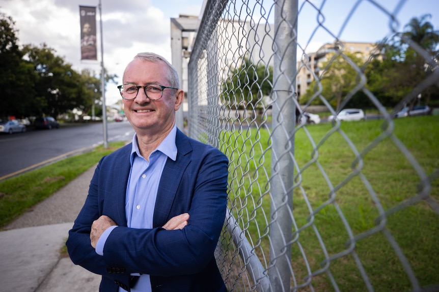 A man in a blue suit jacket posing for a photo.
