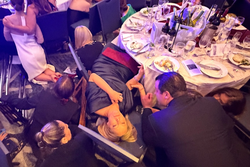 Guests take cover after hearing gunshots at the White House correspondents' dinner.