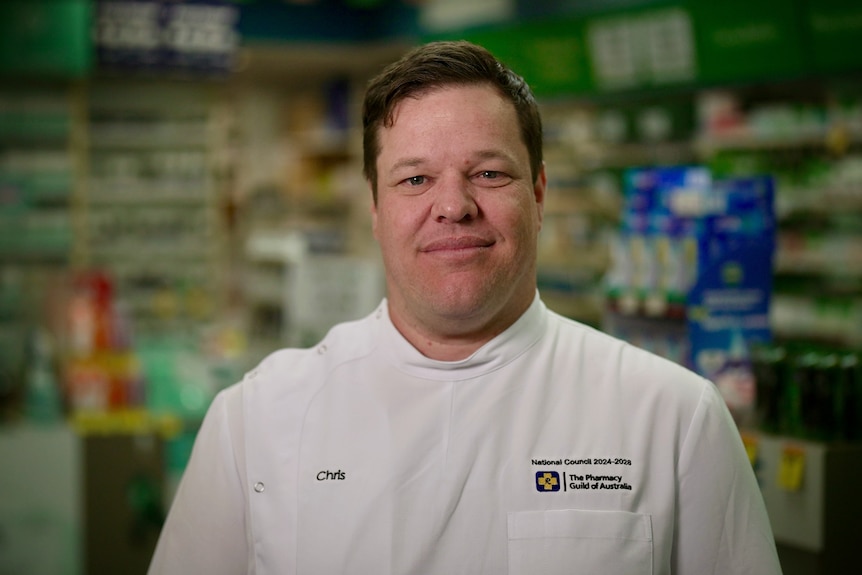 A man in a chemist uniform inside a pharmacy