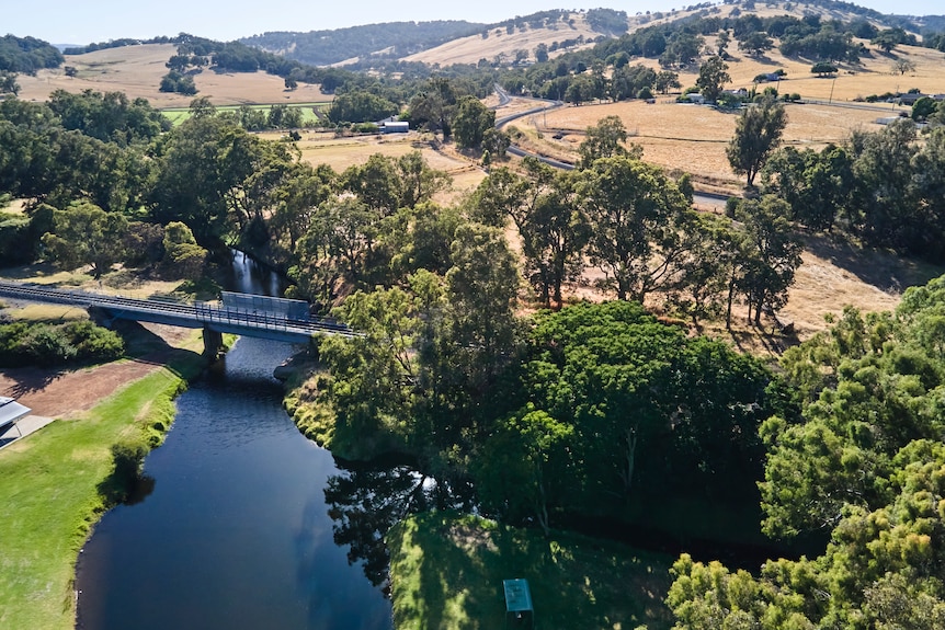 A drone shot of a river surrounded by fields and trees.