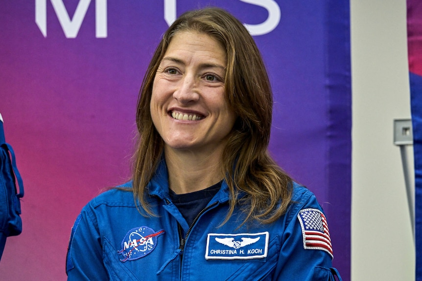 Astronaut Christina Koch smiling wearing a blue NASA suit