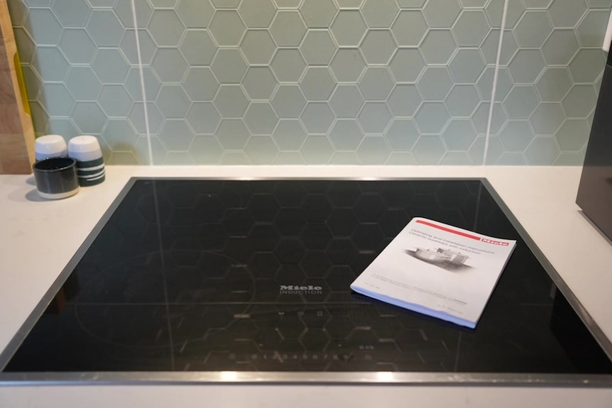 An induction cooktop with an instruction manual placed on top.
