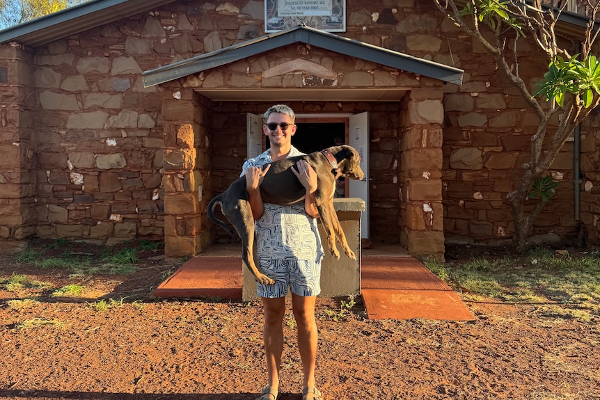 a man outside a church holding a dog