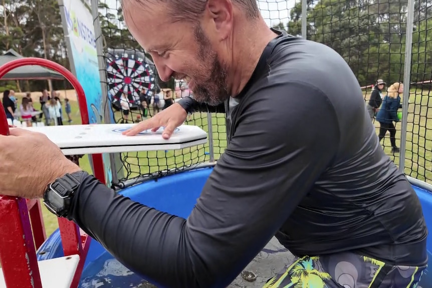 A man climbs out of a dunk tank