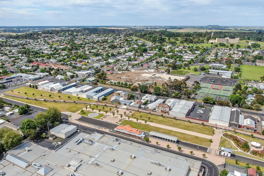 An aerial photo shows a large rectangle patch of grass marked with palm trees and a bitumen track running through.