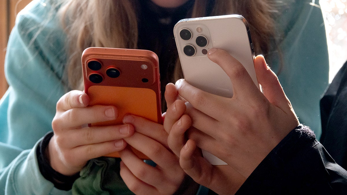 Two teens looking at their iPhones