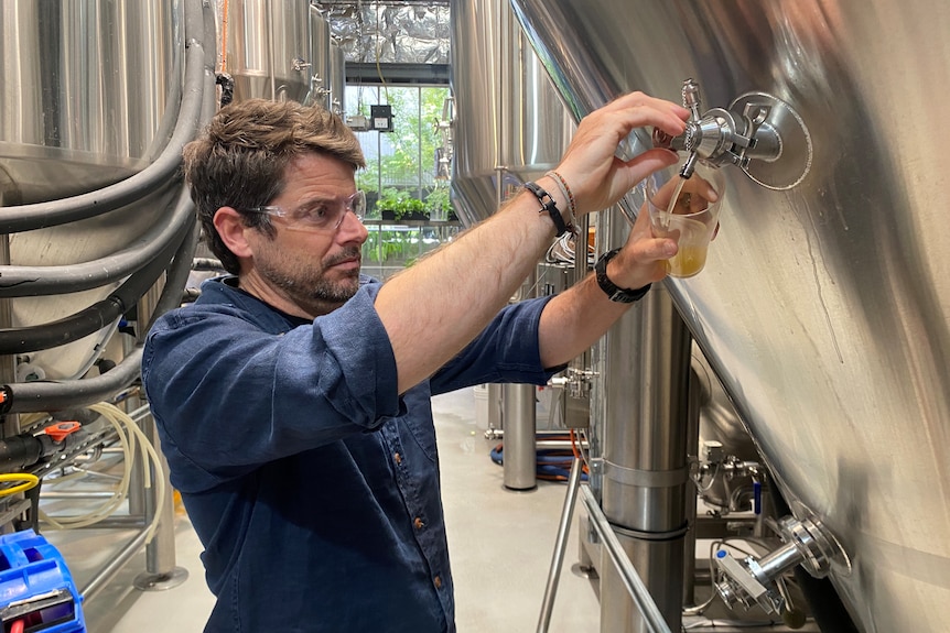 A man in a brewery pouting beer.