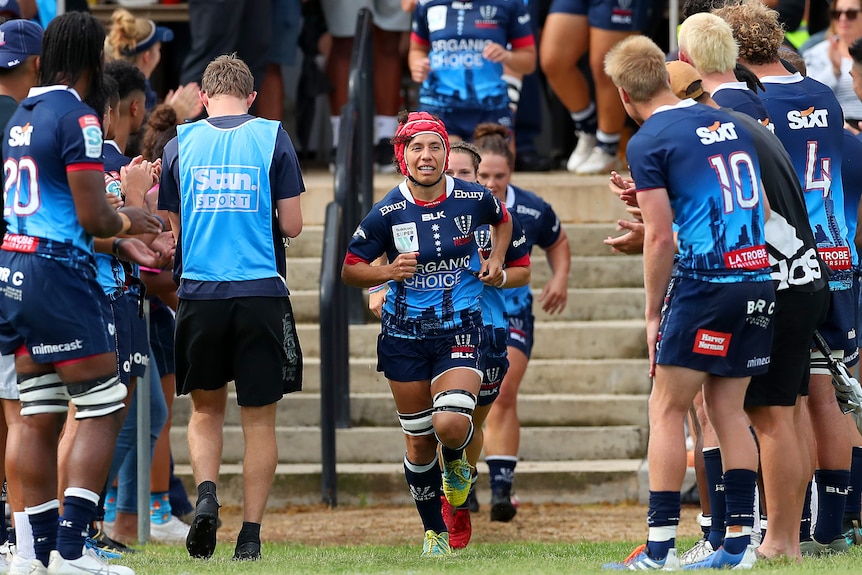 Melanie Kawa (c) of the Rebels leads the Rebels out to the field.