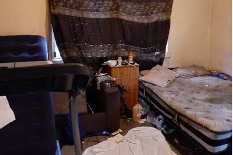 a squalid bedroom with a sheet over the window