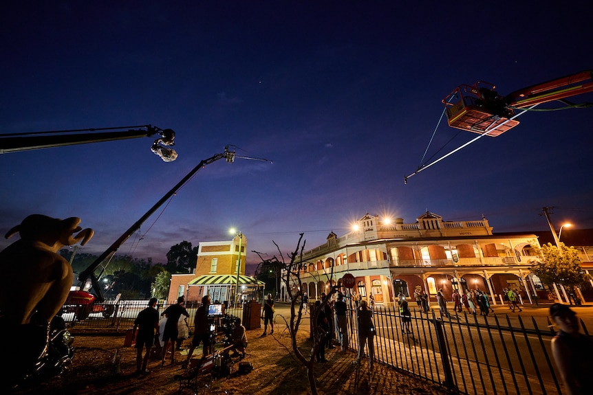 Cameras and lights set up at night filming an old building.