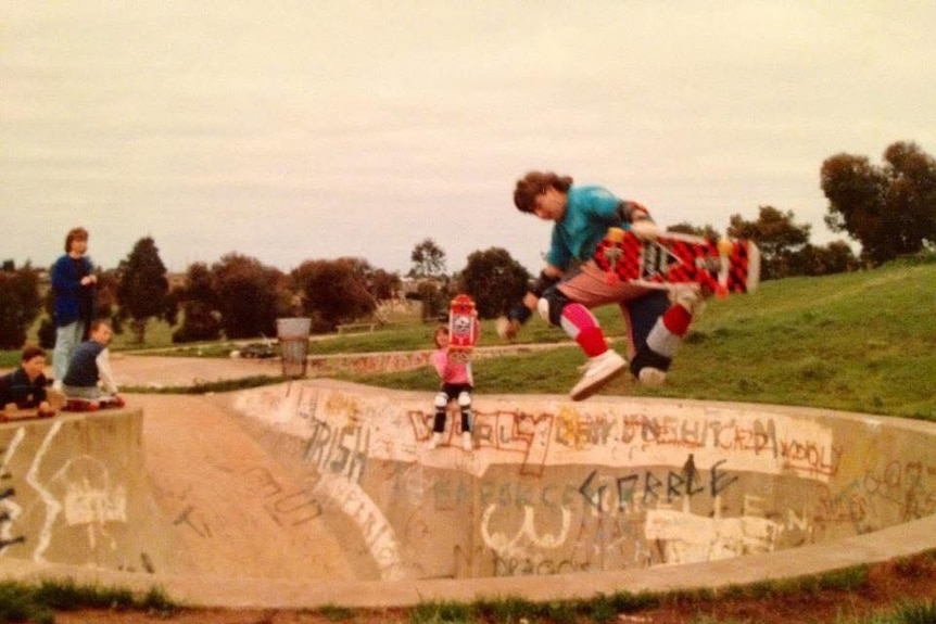 A 1980s photograph of a young man midair at a skate bowl.
